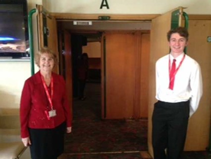 Front of House uniform - female staff wearing red top with black trousers and male staff wearing a white shirt with a red tie